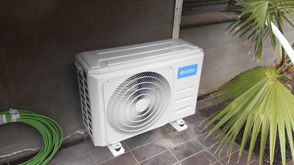 Aire acondicionado en el exterior de un patio al lado de una planta